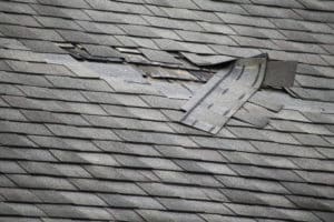 A badly damaged roof with missing shingles in need of repair, Iowa winter roof damage, roof wind damage, shingle repair Des Moines IA